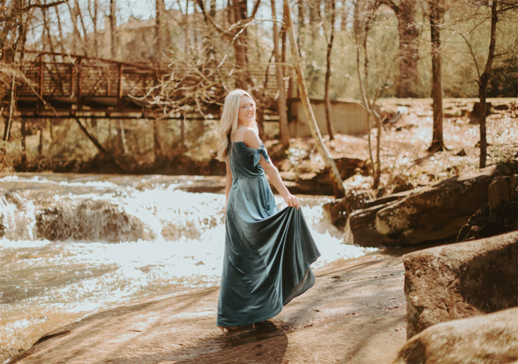 A young lady is standing in the forest, wearing AW velvet bridesmaid dress.