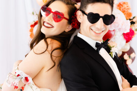 A couple are wearing colored glasses and laughing