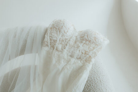 Close-up of a lace wedding dress draped over a textured chair.